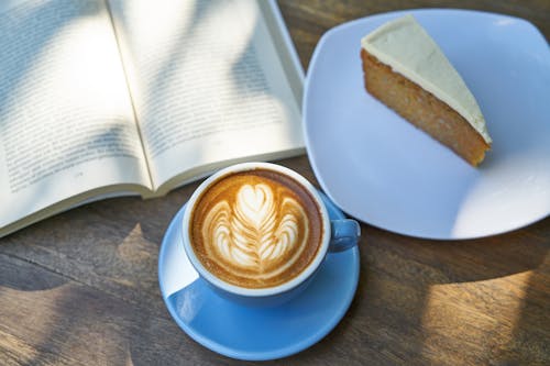 Coffee Latte Beside Book and Cake