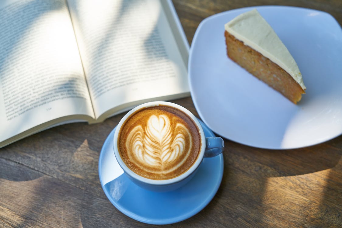 Coffee Latte Beside Book and Cake