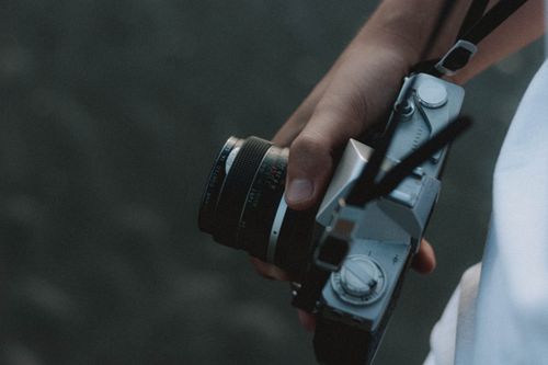 Free From above of crop unrecognizable person with retro photo camera on blurred background Stock Photo