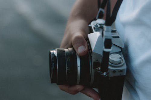 Faceless photographer showing old photo camera on street