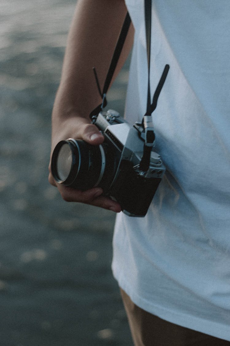 Anonymous Photographer Demonstrating Vintage Photo Camera Near Ocean