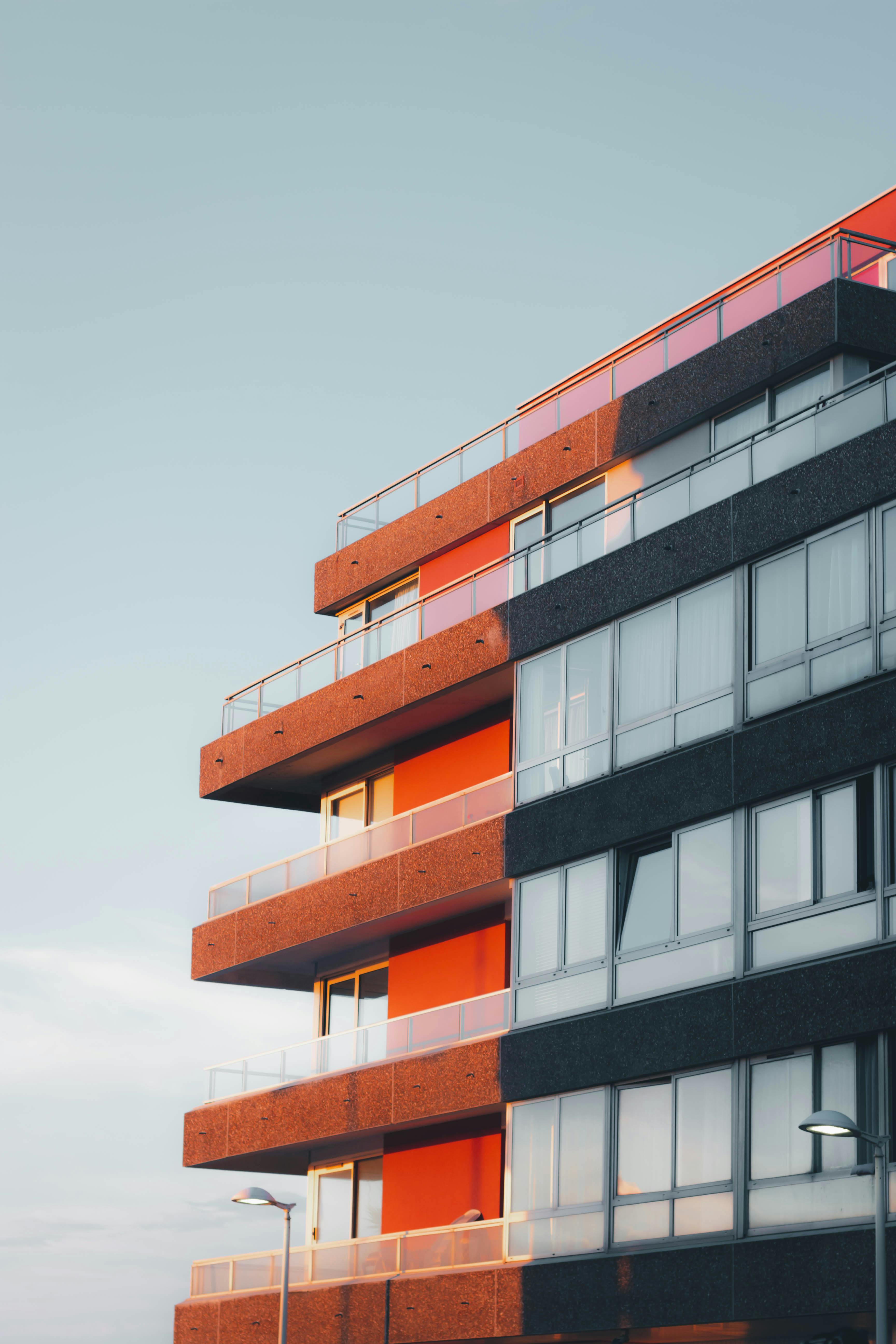 Free Stylish multistory apartment with glass balconies and modern design against a clear sky. Stock Photo