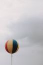 Big balloon with various colors located under cloudy gray sky in gloomy weather