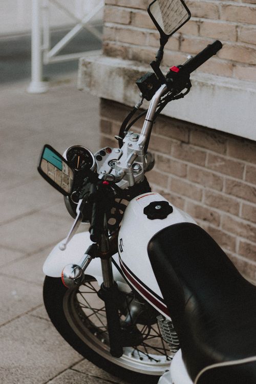 Free White motorbike parked on pavement on street near brick building on gloomy day Stock Photo