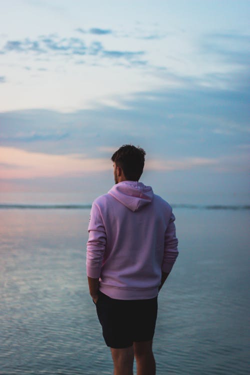 Anonymous man admiring seascape at sunset