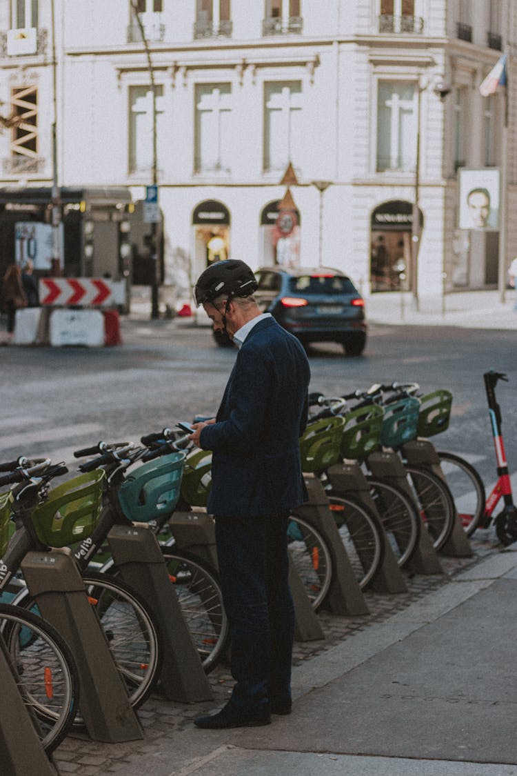 Man In Suit And Helmet Renting Bicycle On Street