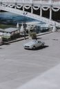Sparkling car crossing calm sunny embankment decorated with columns located in modern city