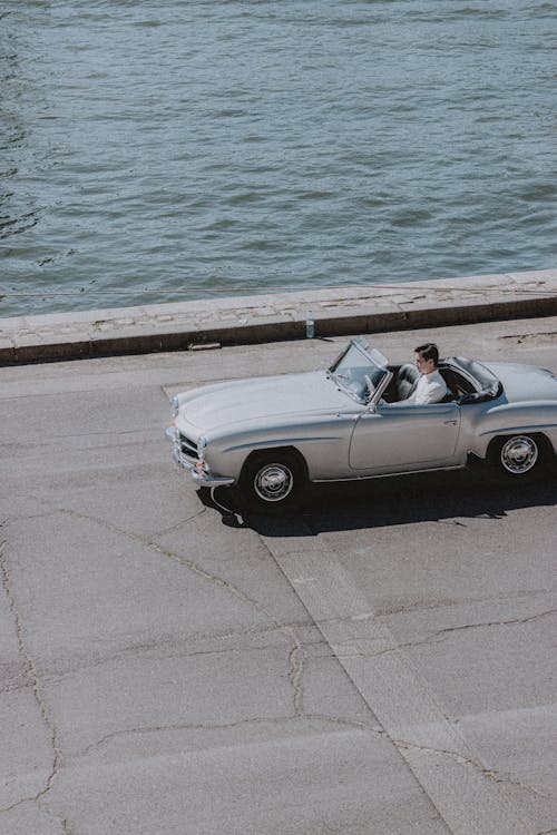 Man in white shirt travelling in silver car