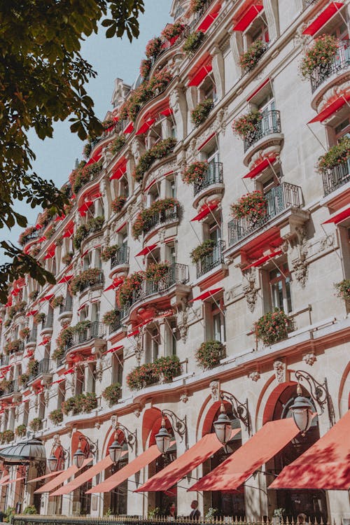 Exterior of wide old building with red terraces and canopies on sunny clear afternoon