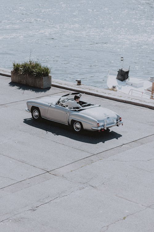 Old silver car driving on road