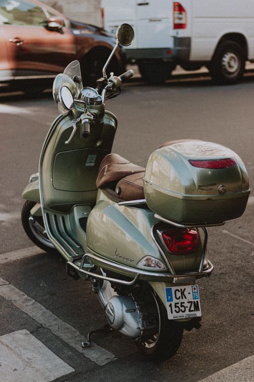 Free Old fashioned sparkling scooter parked on busy street with driving cars in city Stock Photo
