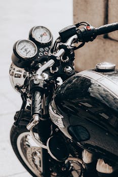 A detailed view of a classic motorcycle's handlebars and speedometer on a city street.