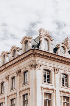 Majestic vintage building facade with ornate details under a cloudy sky, showcasing European architectural style.