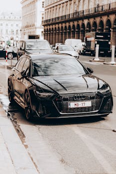 Sleek black car parked on a city street, showcasing luxury and power.