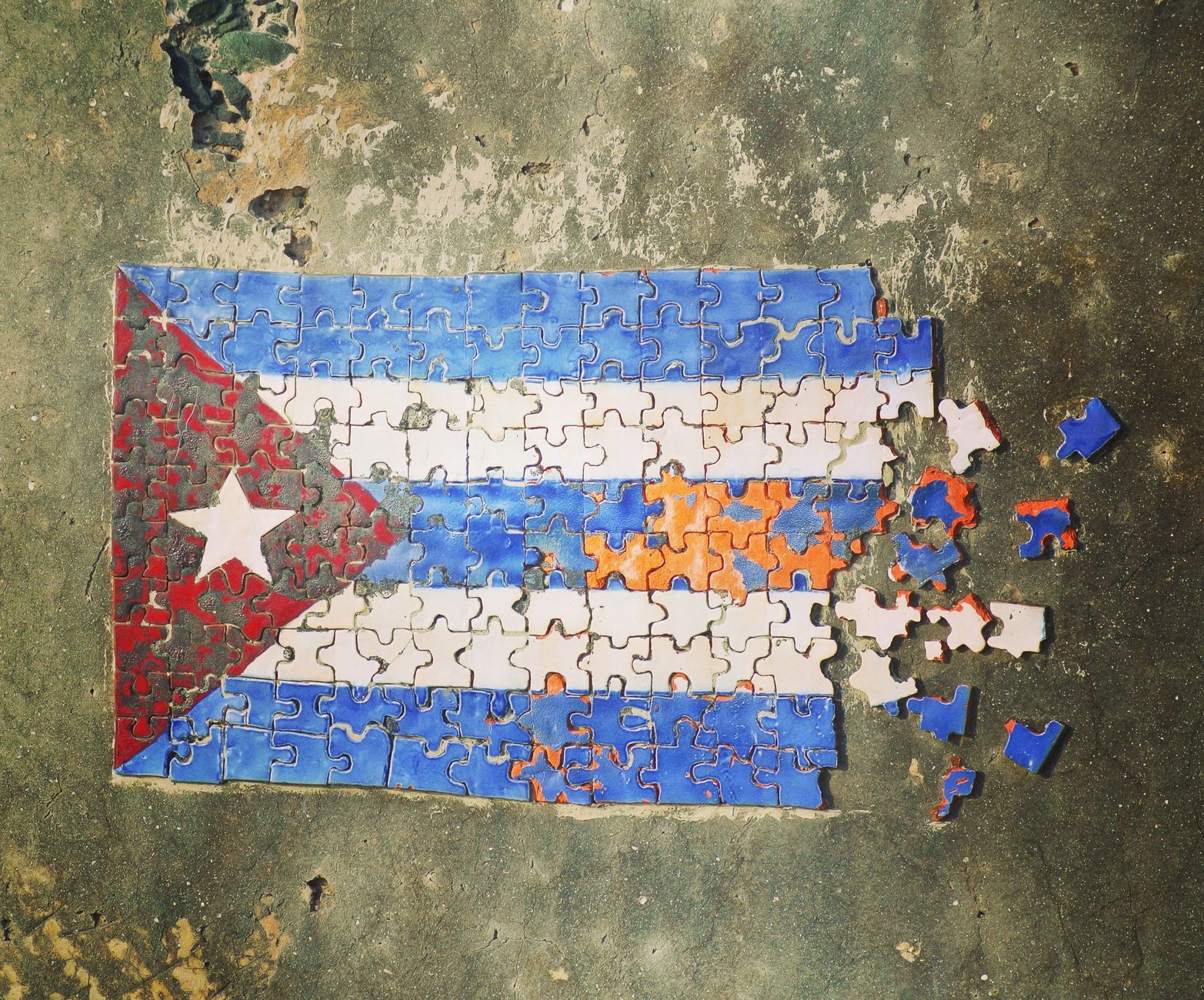 An incomplete Cuban flag jigsaw puzzle on a distressed surface, symbolizing patriotism and history.