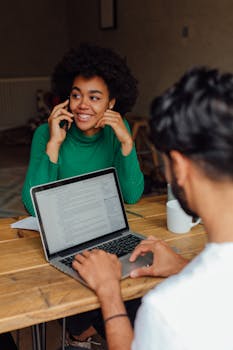 两名同事带着笔记本电脑和手机，在舒适的办公空间里一起工作