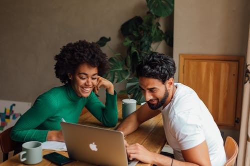 Photo of a Man and Woman Looking at the Screen of a Laptop