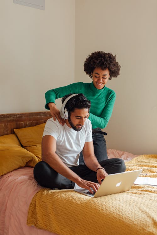 Homme En T Shirt à Col Rond Blanc Assis Sur Le Lit à L'aide De Macbook