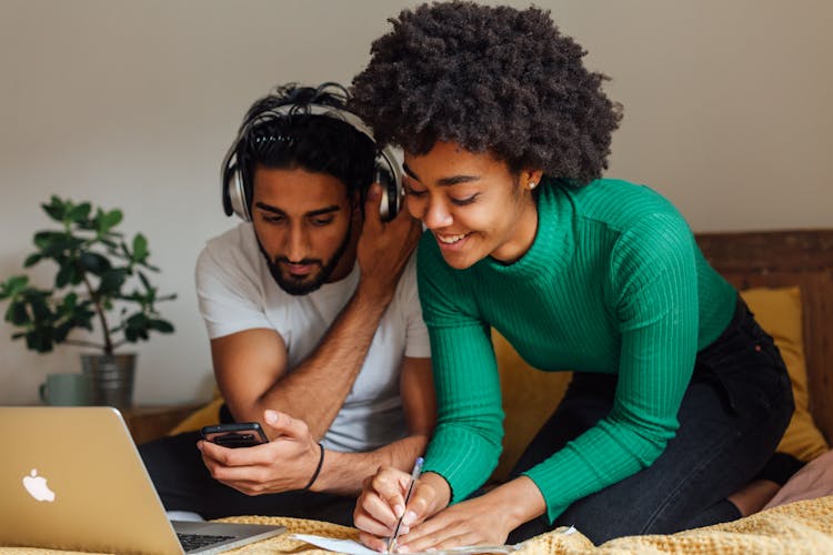 Young Couple Sitting On Bed Working At Home