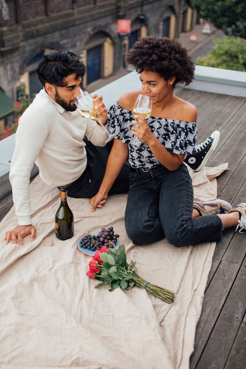 Man and Woman Sitting on Rooftop Drinking Wine