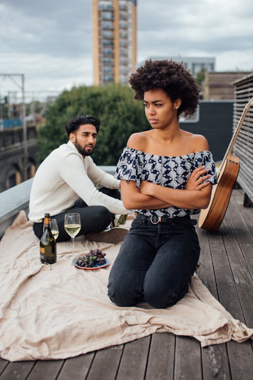 Woman in Blue Denim Jeans Sitting Beside Man in White Long Sleeve Shirt