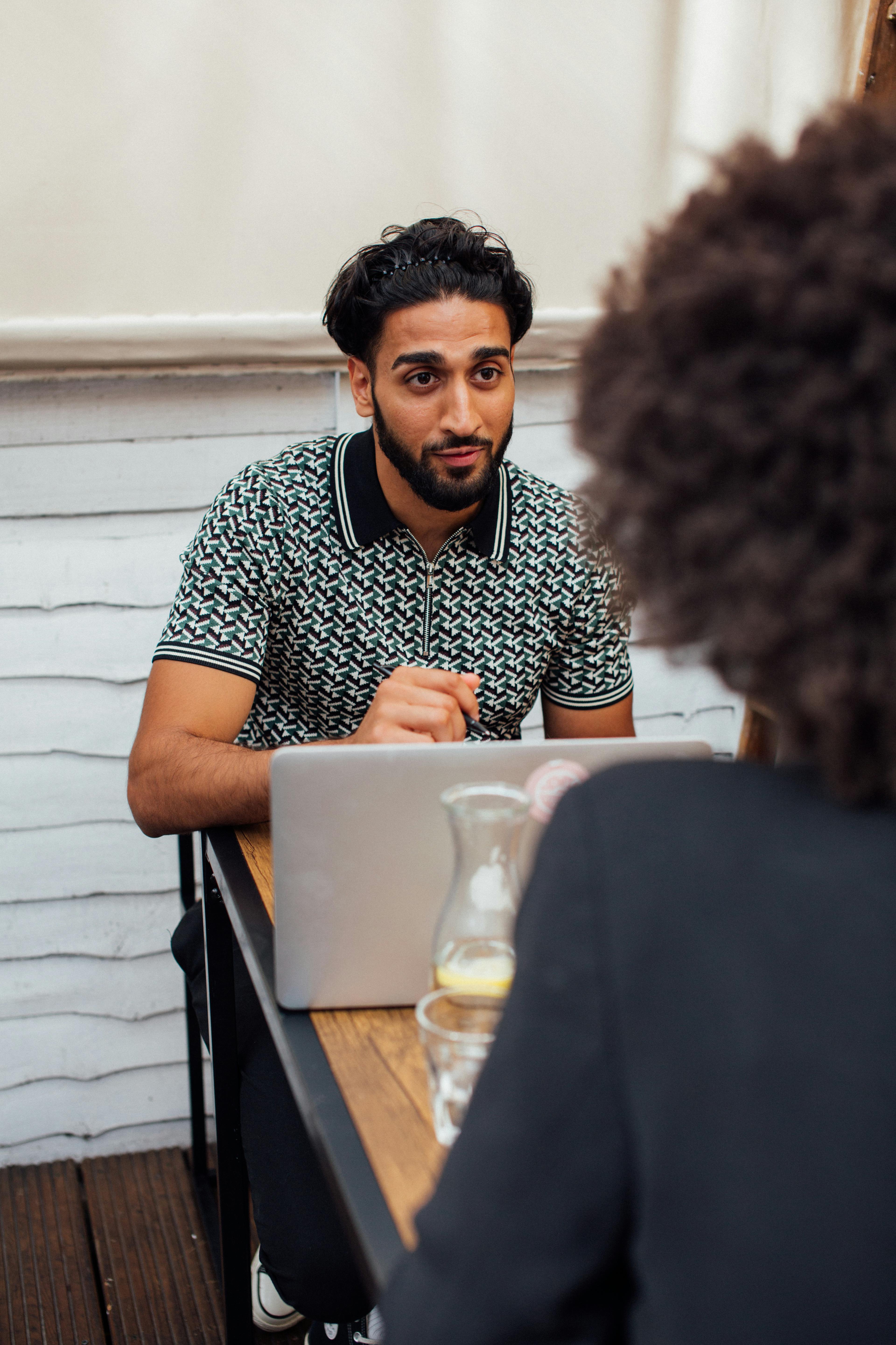 man in black and white polo shirt sitting in front of laptop