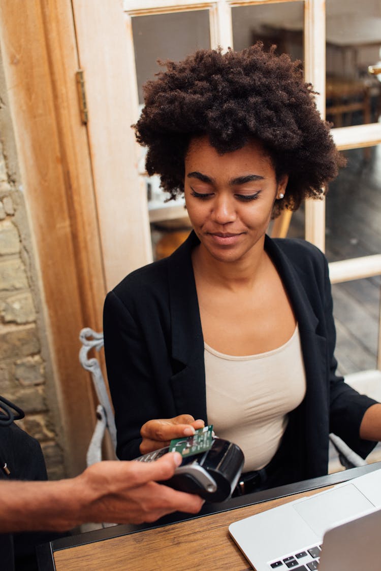 Young Woman Sitting At A Table Paying Contactless With A Bank Card