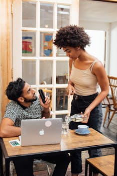 Casual conversation between customers with technology and coffee in a cafe setting.