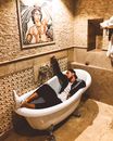 Woman in Black Shirt Lying on White Bathtub