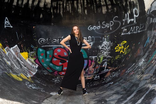 Woman in Black Dress Standing Beside Graffiti Wall