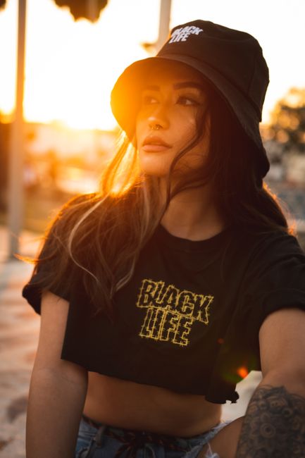 Confident trendy female looking away in shiny sky while resting alone on street in back lit