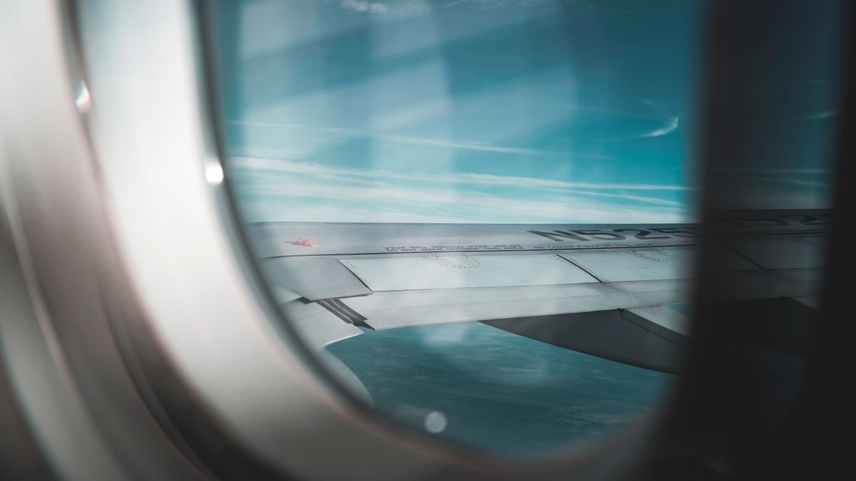A serene view of an airplane wing against a backdrop of blue sky from a window seat.