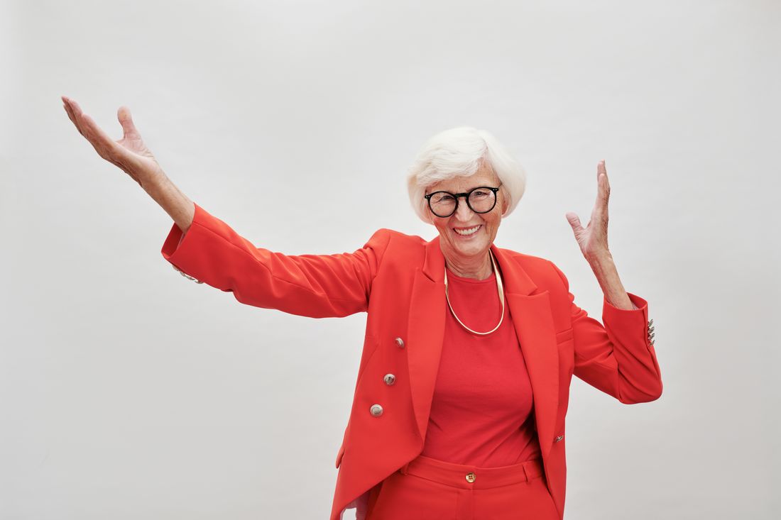 A joyful senior woman with white hair and eyeglasses
