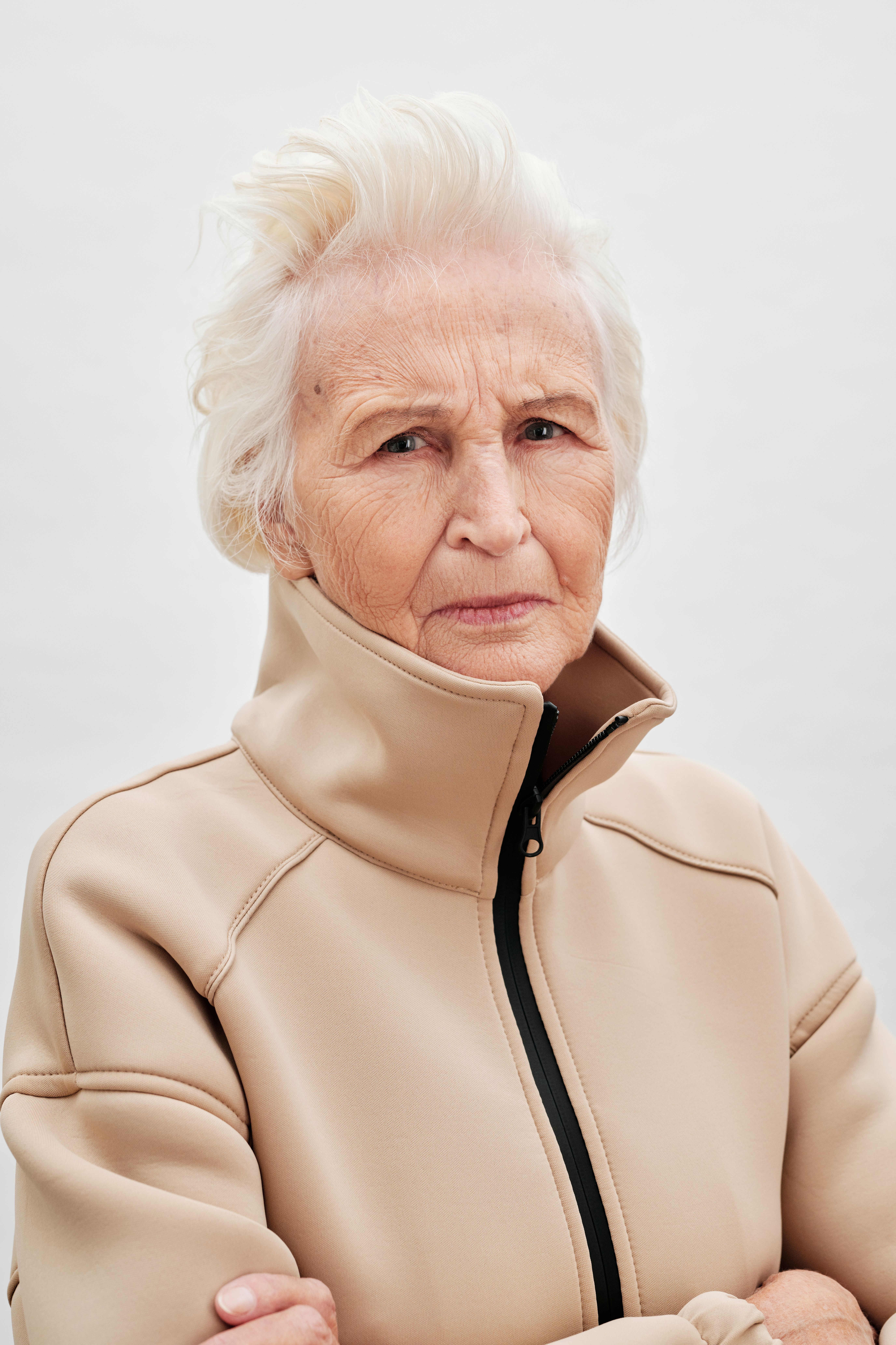 Close-up portrait of an elderly woman with white hair and wrinkles, exuding confidence and style.