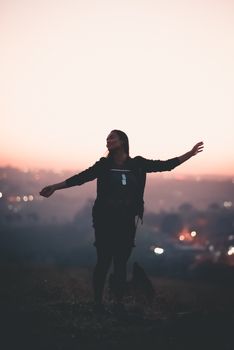 一个女人伸出双臂，在户外享受日落时分的宁静时刻