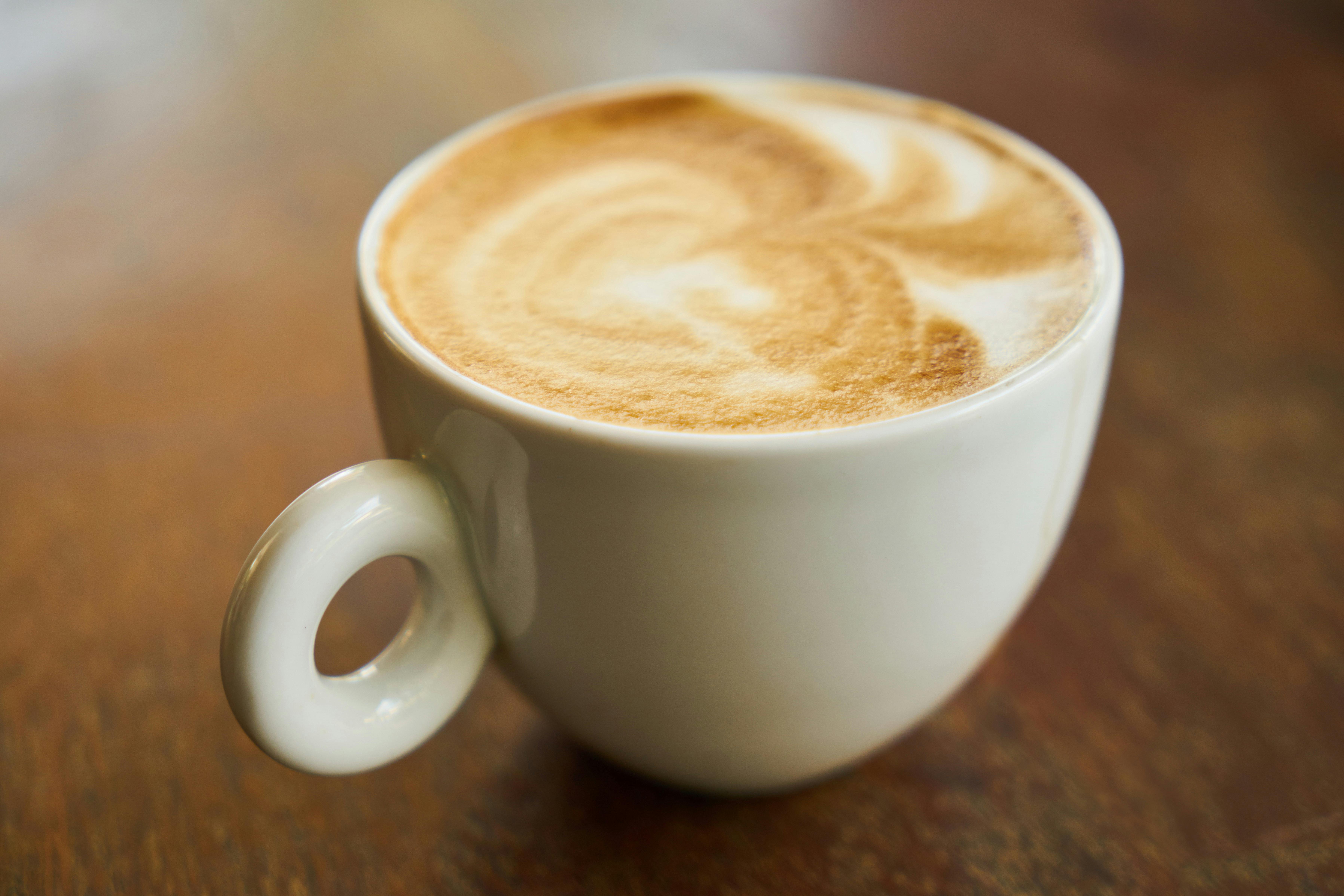 Person Holding Cup of Coffees on Table · Free Stock Photo