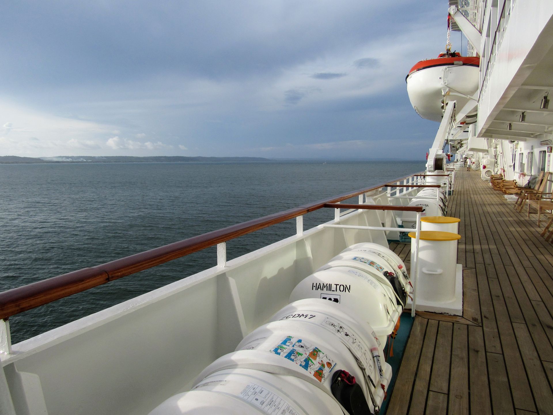 The deck of a cruise ship at open sea, with the horizon visible in the background.