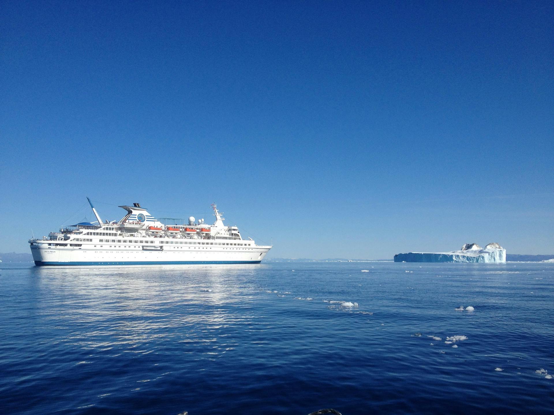 Scenic view of a cruise ship near a majestic iceberg in the waters of Greenland.
