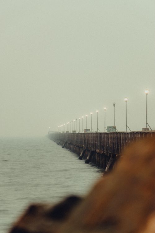Free Peaceful coast surrounded with rippling of water of river with long wooden pier in fog Stock Photo