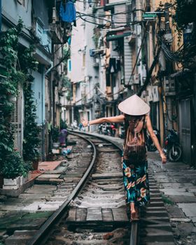 一位戴着圆锥帽的妇女走在越南的城市火车轨道上
