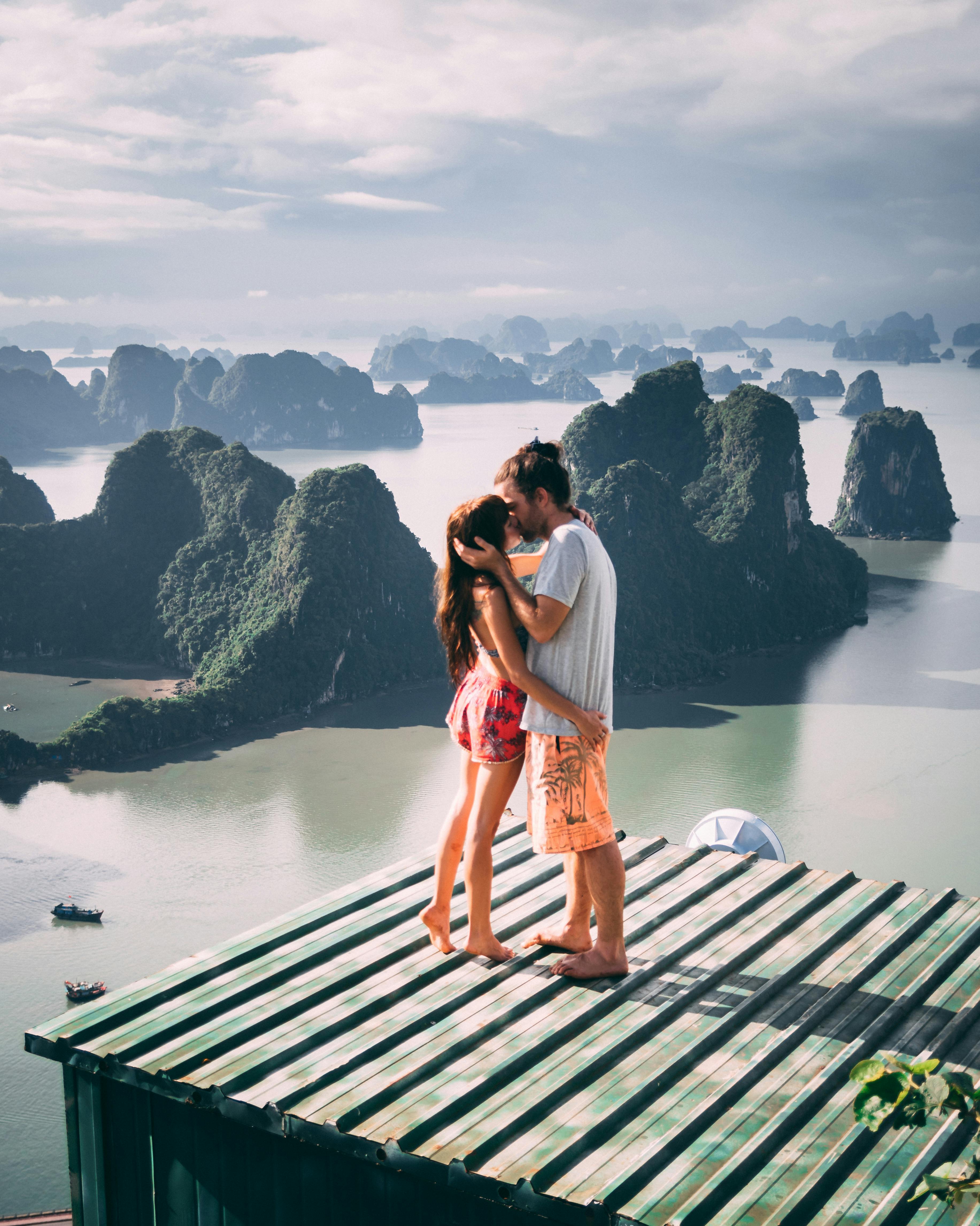 一对夫妇在屋顶上拥抱，可以看到下龙湾石灰岩岛屿的壮丽景色