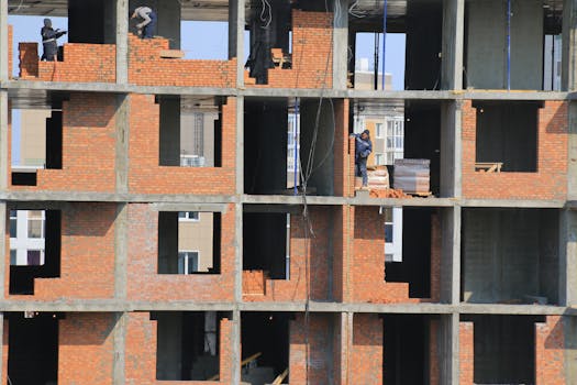 View of construction workers building brick walls on an unfinished urban apartment.