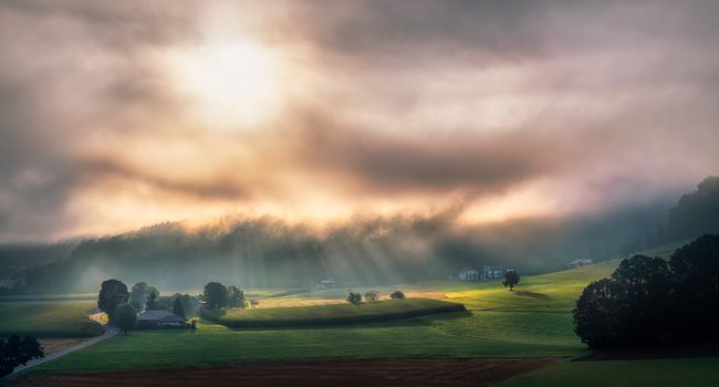 Dramatic countryside landscape in Gmunden with sunlight streaming through clouds.