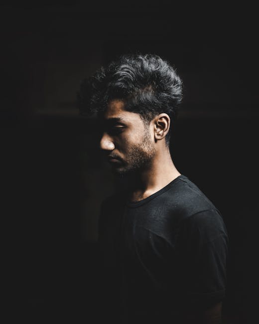 Moody portrait of a man in a black shirt with artistic lighting, India.