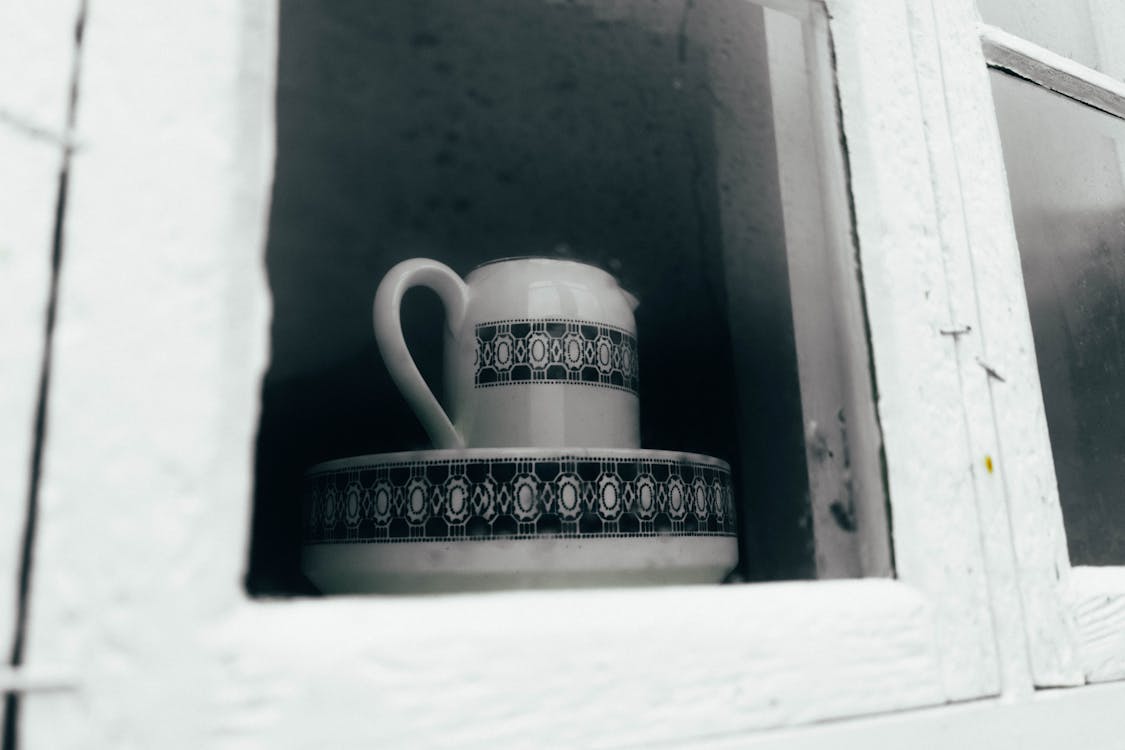 Ceramic Teapot and Bowl Beside a Wooden Framed Glass Window