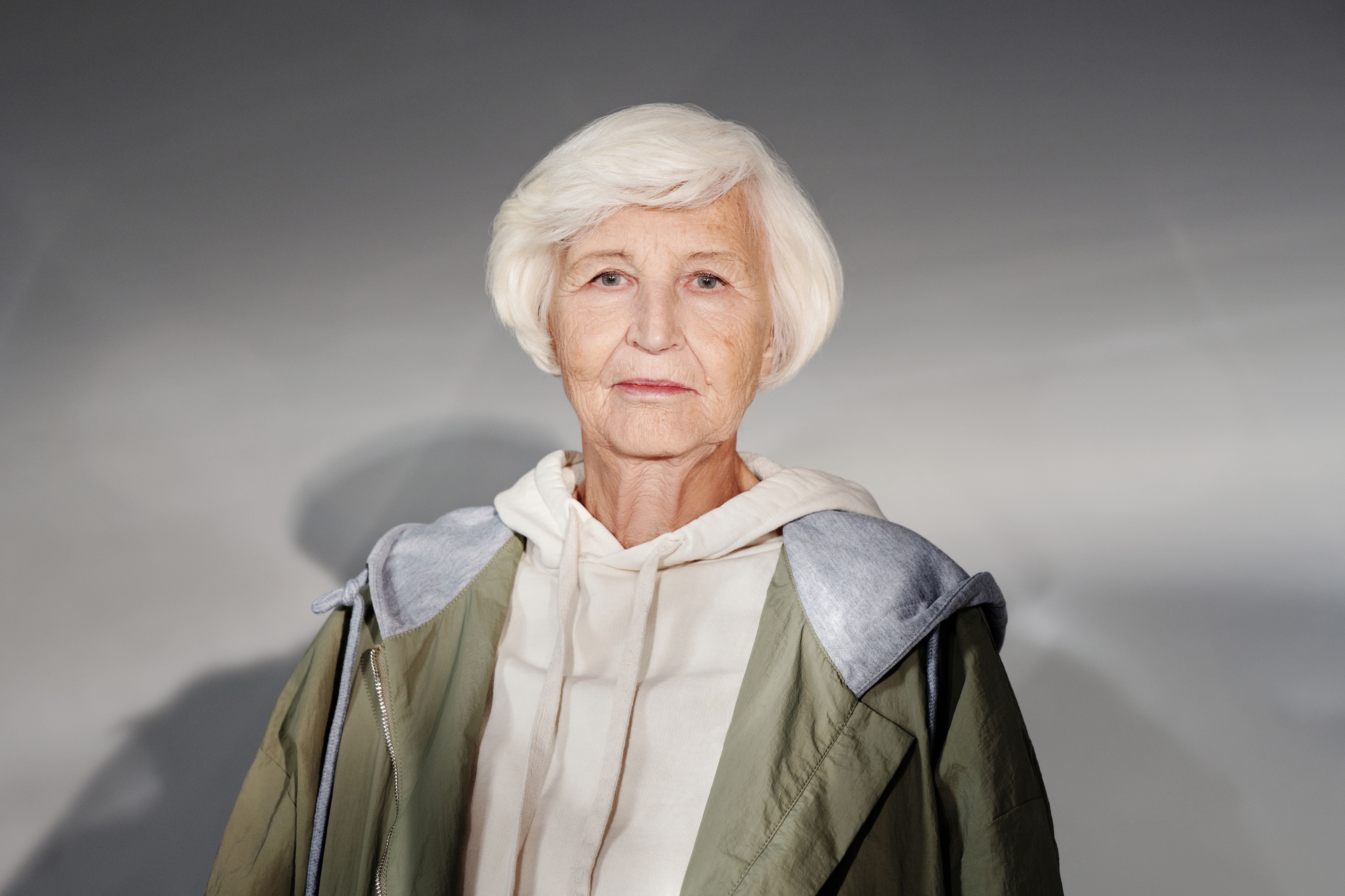 Portrait of a senior woman in a fashionable hoodie and coat, exuding confidence and style.