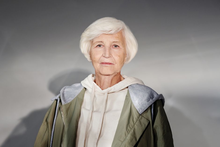 Portrait of a senior woman in a fashionable hoodie and coat, exuding confidence and style.