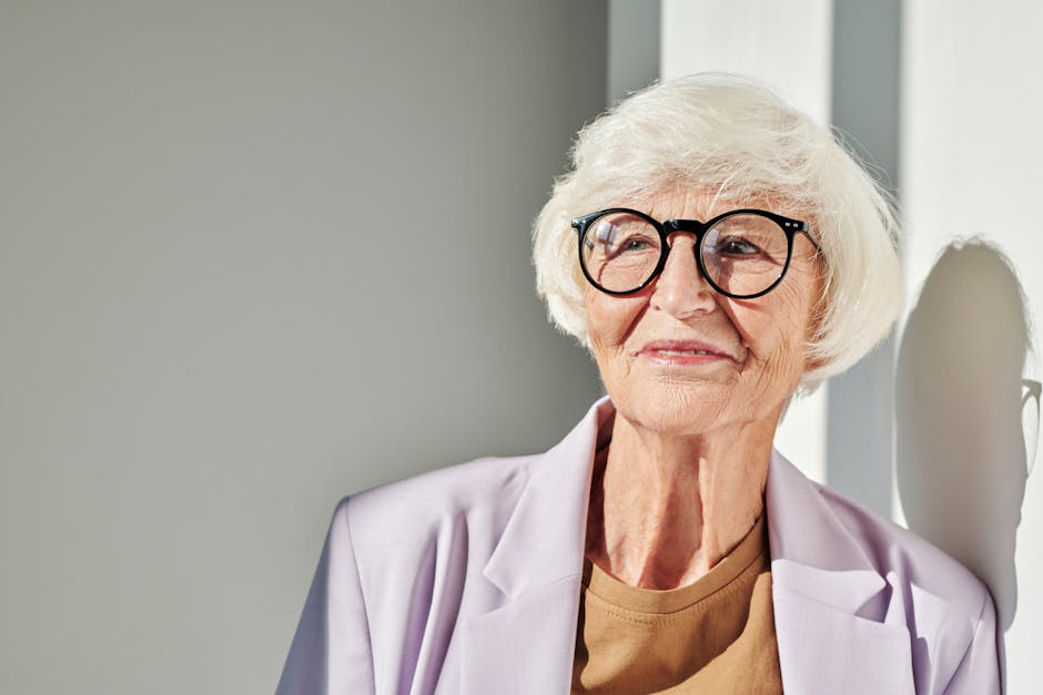 Close-up of a stylish senior woman with glasses in soft light.