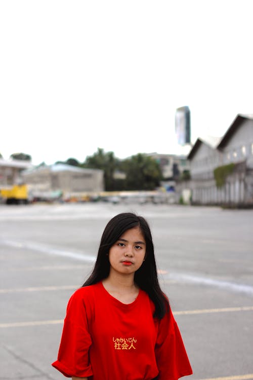 Woman in Red Crew Neck Shirt Standing on Concrete Ground