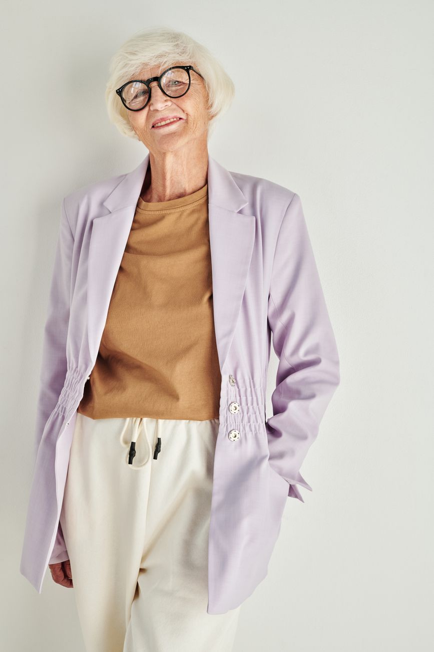 Chic senior woman in a lavender blazer smiles with confidence, exuding style and grace.